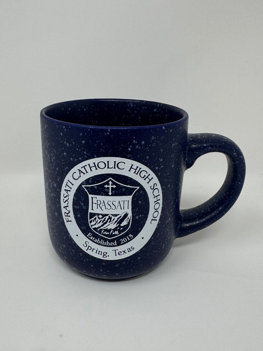 A dark navy blue speckled ceramic mug with a white printed circular logo for Frassati Catholic High School, shown on a plain light background.